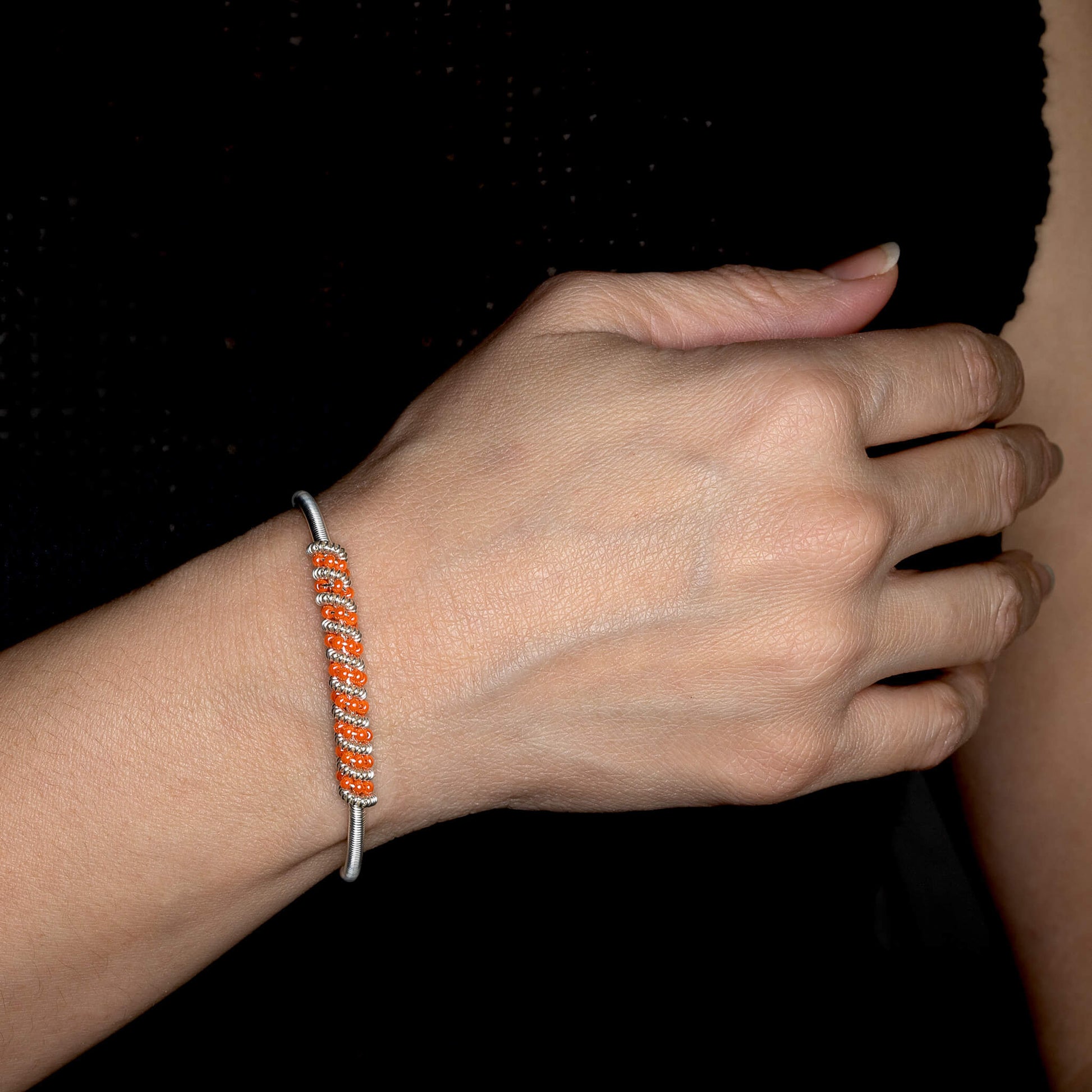 Siegen Silver Bracelet on a model. Silver Color Cuff Bracelet with Orange seed beads crystals. Wire wrapped bracelet.