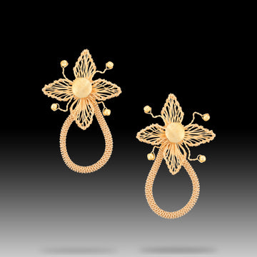 Gold Alambrismo four-petal flower earrings with fine wire woven across each petal like thread on a loom, above a tightly coiled teardrop loop.