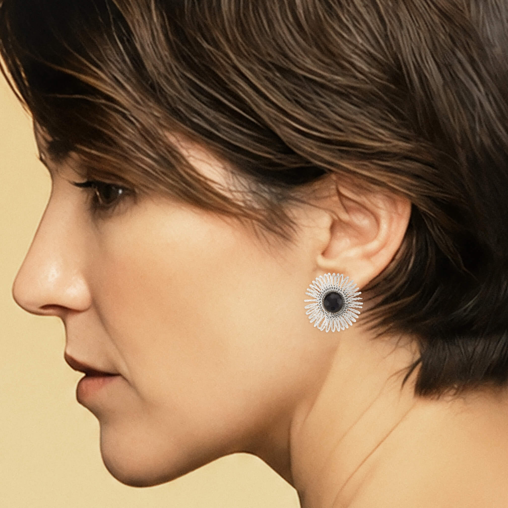 Close-up of a silver garnet sunburst stud earring showing its 1.5-inch scale and woven wire detail