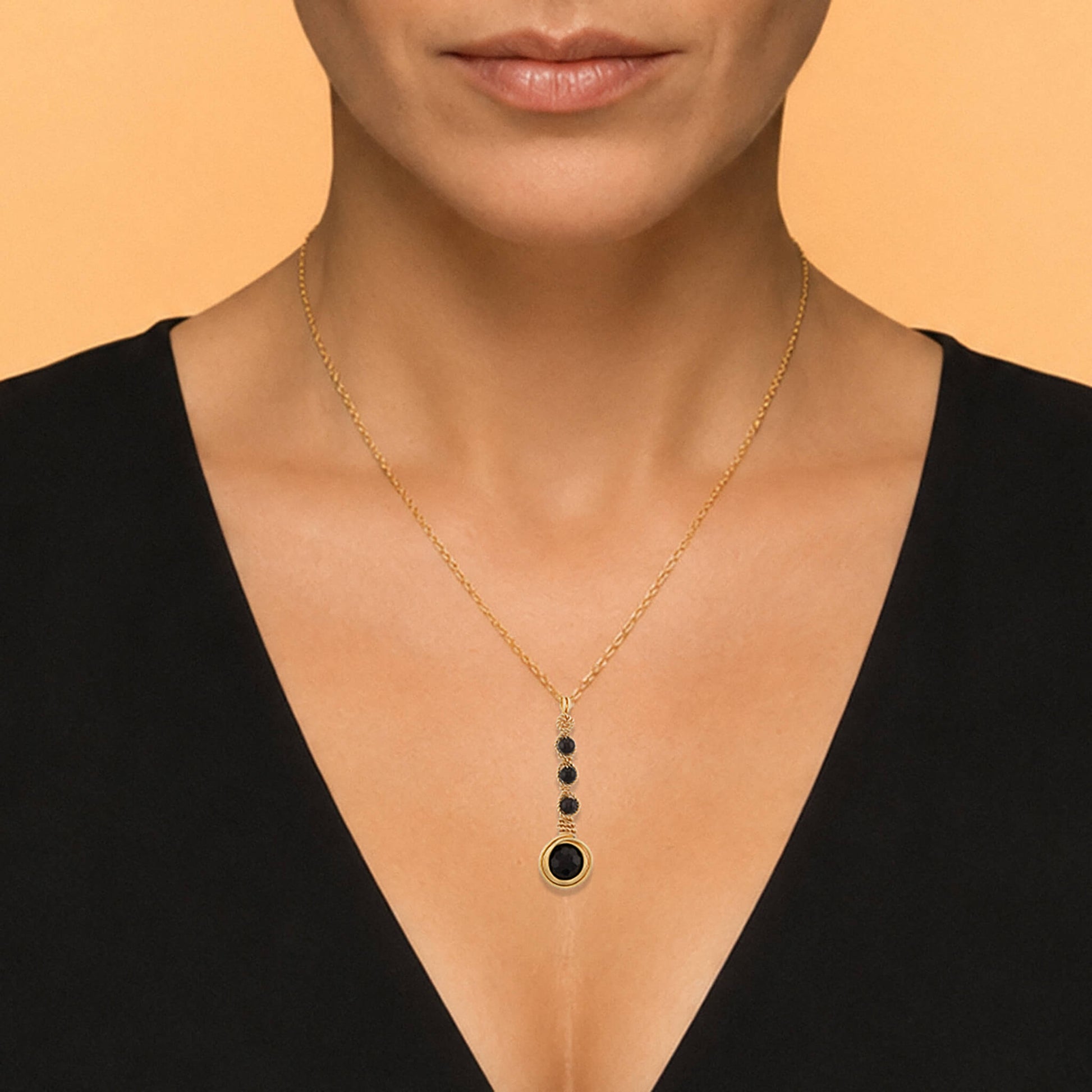 Close-up of a gold garnet cascade pendant showing four faceted stones and rounded wire detail