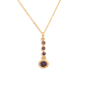 A gold chain necklace with a vertical drop pendant featuring three small round purple Amethyst gemstones and a larger purple Amethyst gemstone at the bottom, set against a plain white background.