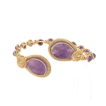 A gold wire-wrapped bracelet featuring three large oval purple amethyst stones and smaller matching purple stones along the chain, set against a plain white background.