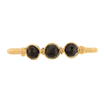 A gold-toned twisted rope cuff bracelet featuring three faceted dark red round Garnet gemstones in bezel settings, shown against a plain white background.