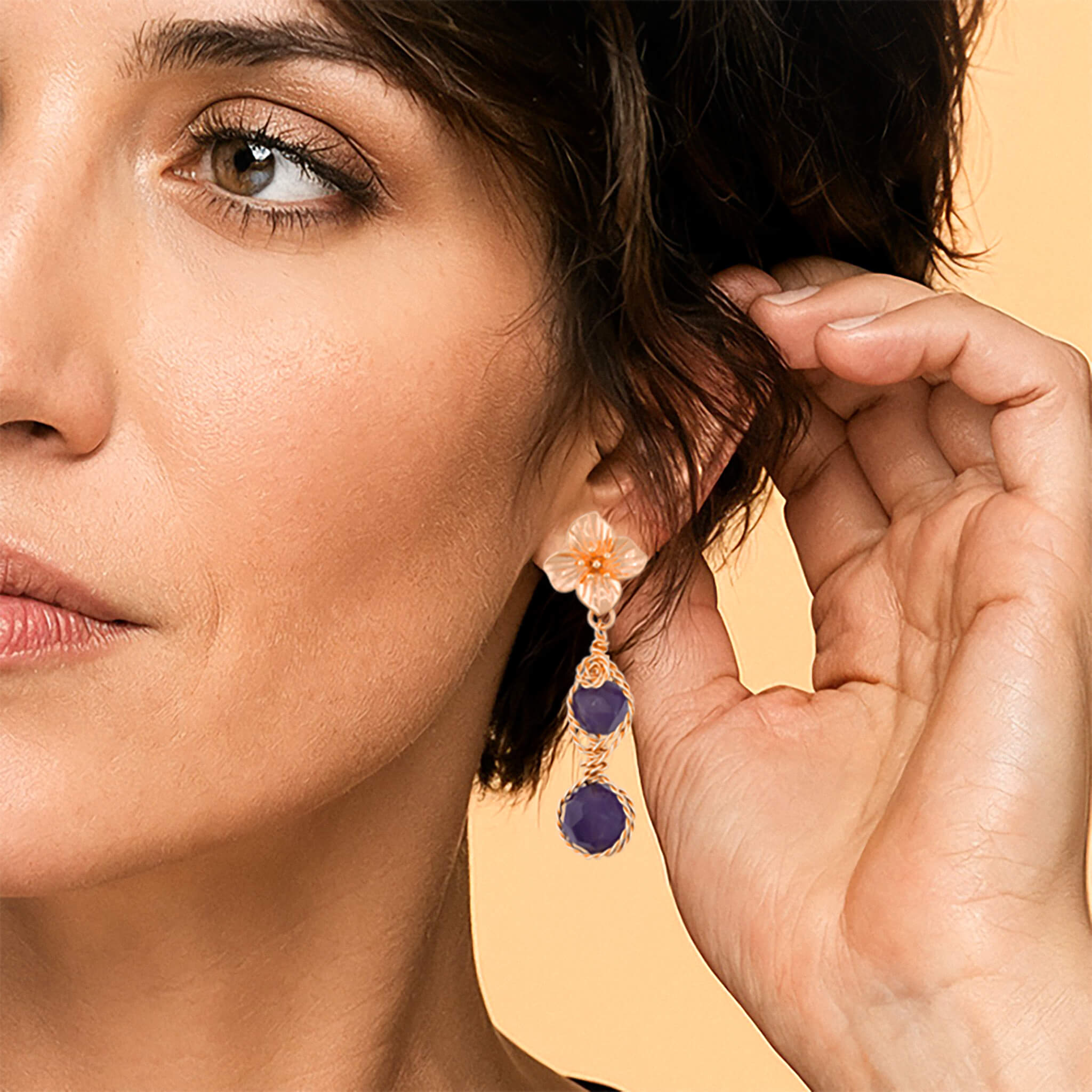 Close-up of gold amethyst flower drop earrings with floral top and wire-wrapped purple gemstones worn on ear