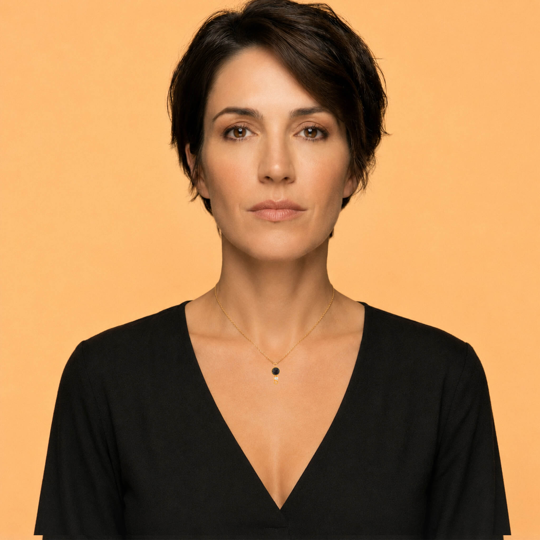 Woman wearing a garnet pearl pendant necklace with a black V-neck top