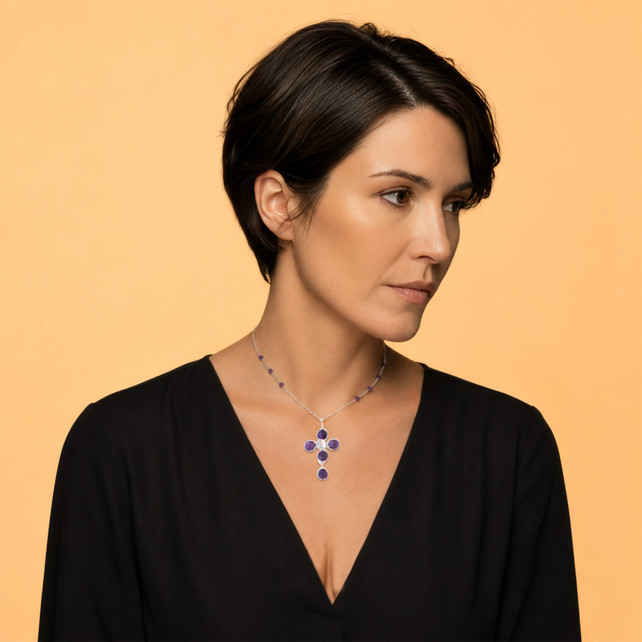 Woman wearing a silver amethyst cross necklace with a black V-neck top