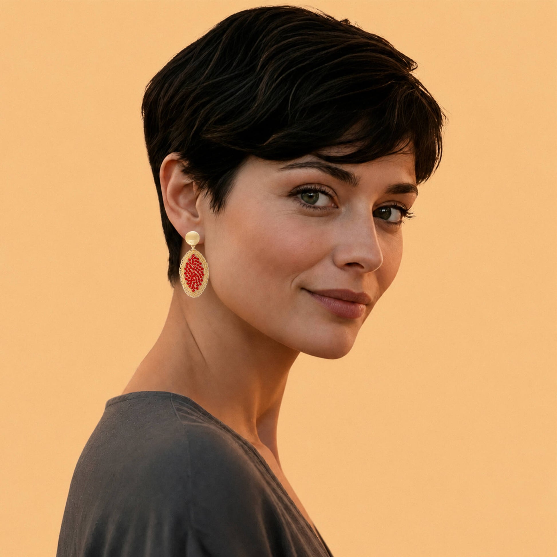 Model wearing a gold red crystal leaf drop earring, styled elegantly to showcase its structural volume and face-framing length against a warm backdrop.