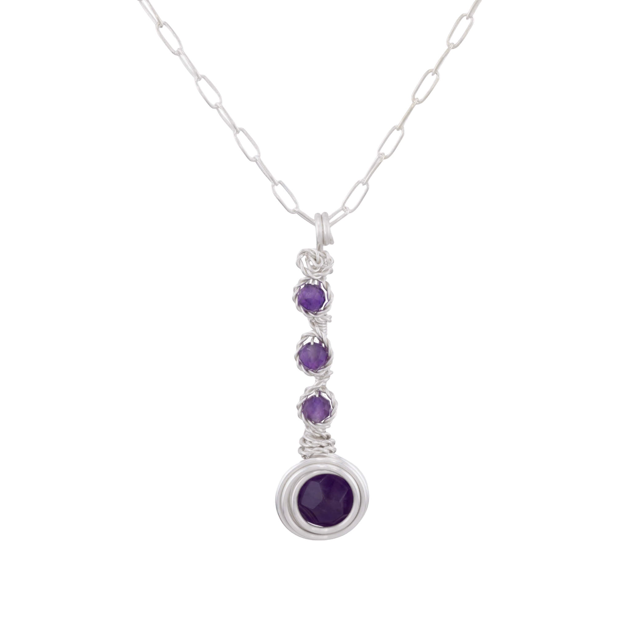 A silver paperclip chain necklace with a vertical drop pendant featuring three small round purple gemstones and a larger oval purple gemstone at the bottom, set against a plain white background.