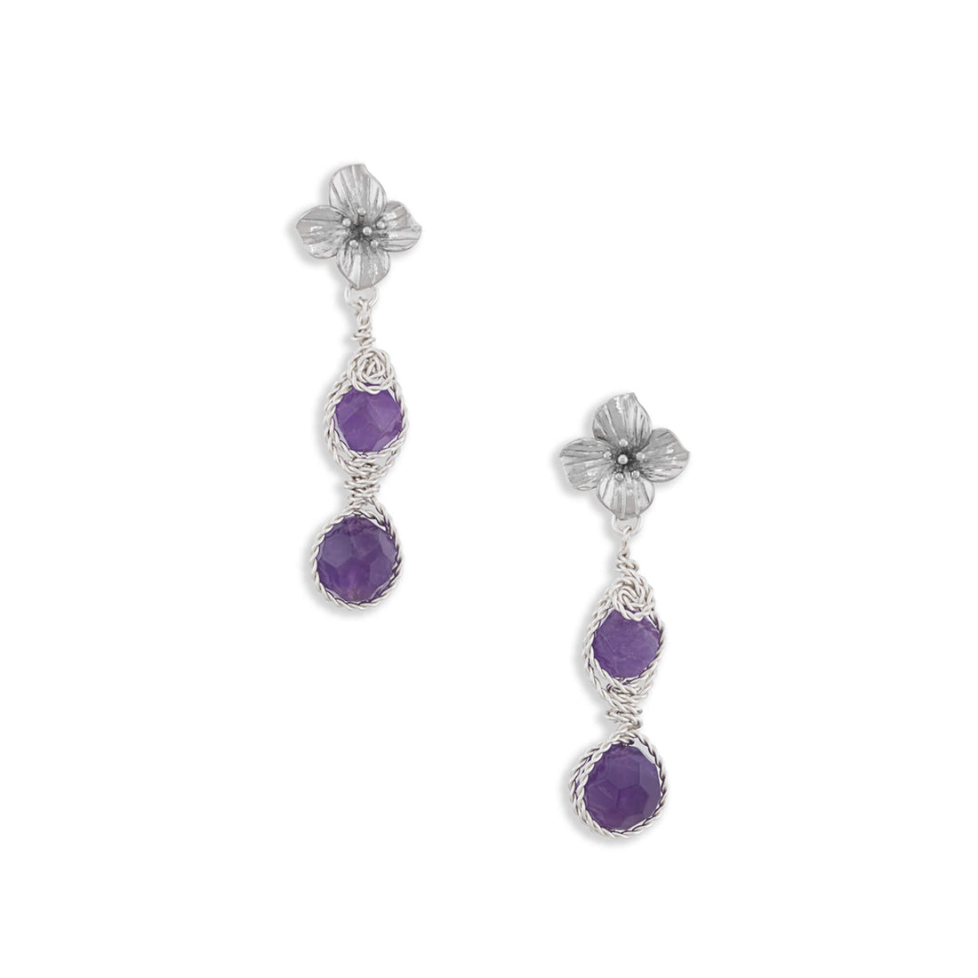 A pair of silver dangle earrings featuring textured flower studs, twisted wire details, and two round purple amethyst gemstones on each earring, set against a plain white background.