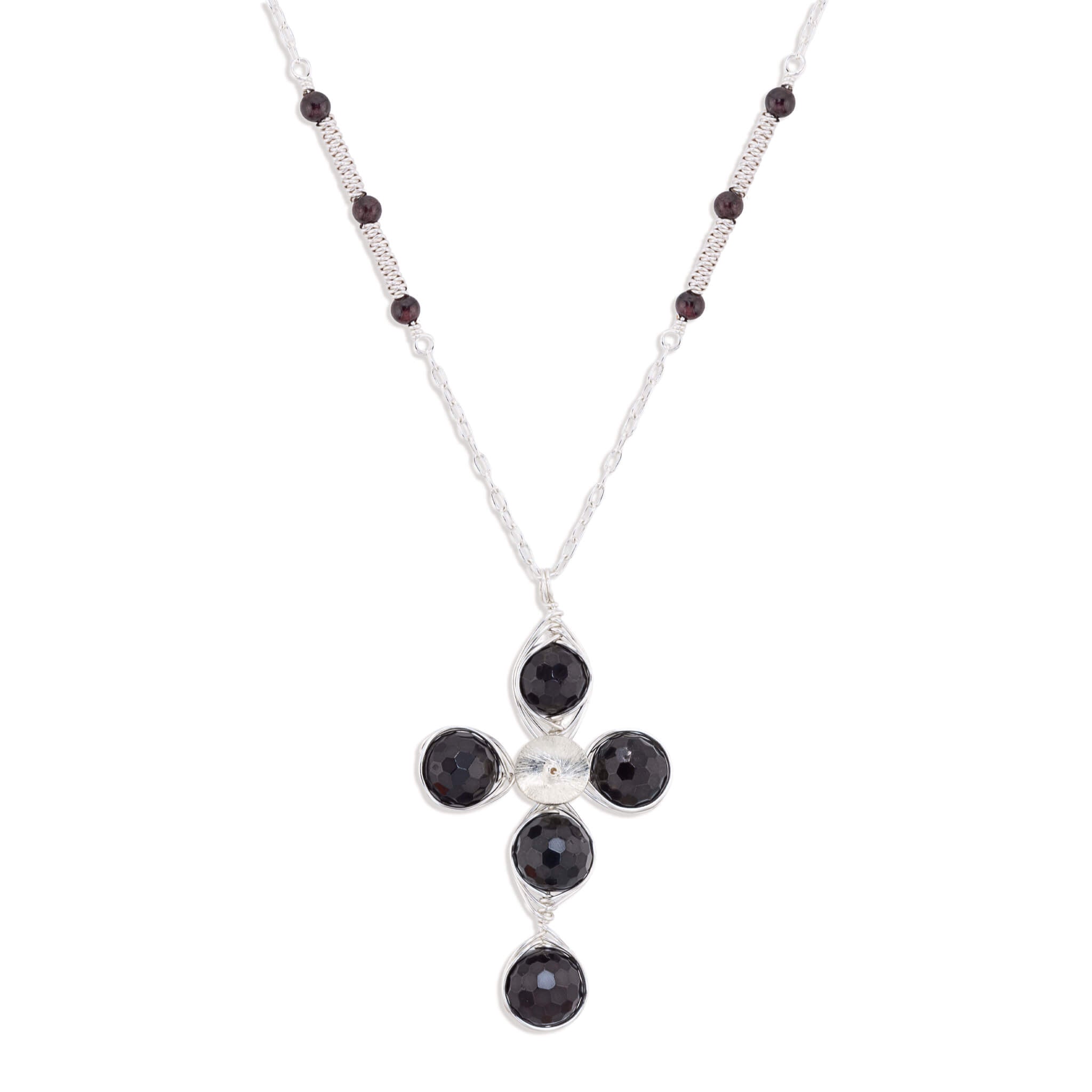 A silver cross pendant necklace featuring four round dark red garnet gemstones and a small silver disc at the center, suspended from a silver chain with small dark red garnet beads.
