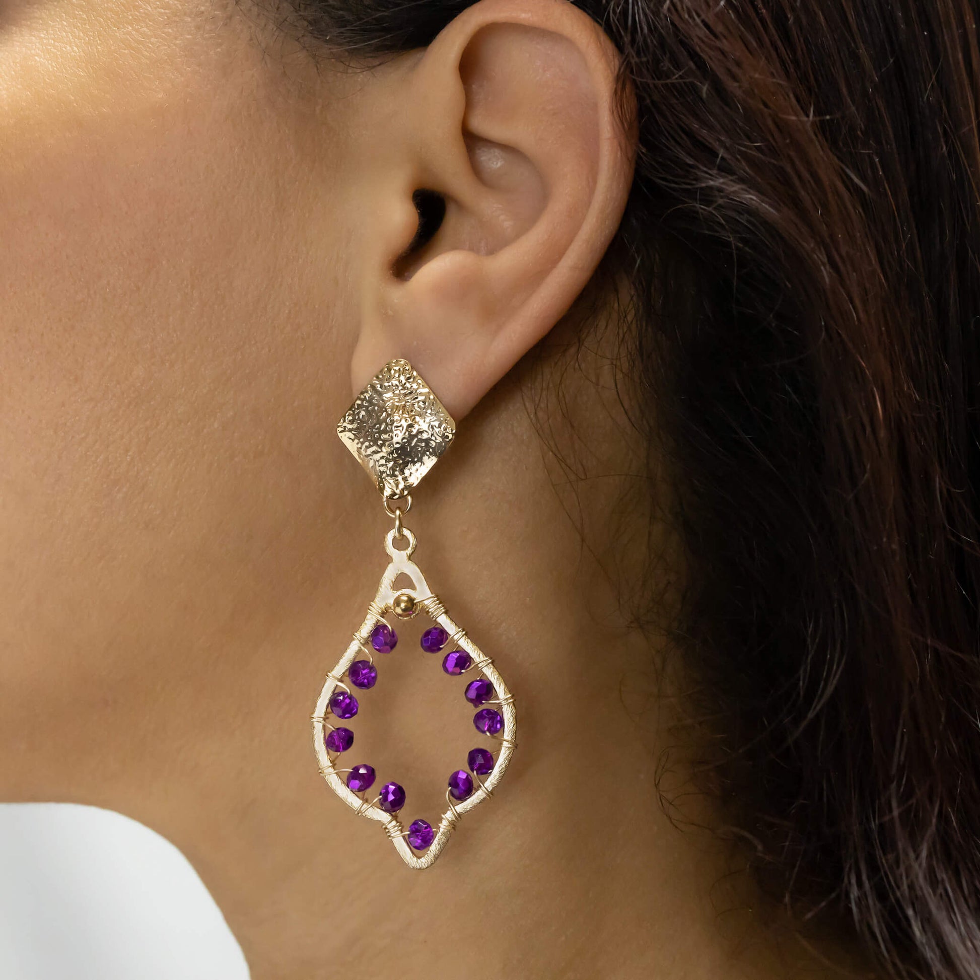 Chaima Earrings on a model. Gold Color Earrings with Purple Crystal Beads. Metal Frame & Wire Wrapped Earrings
