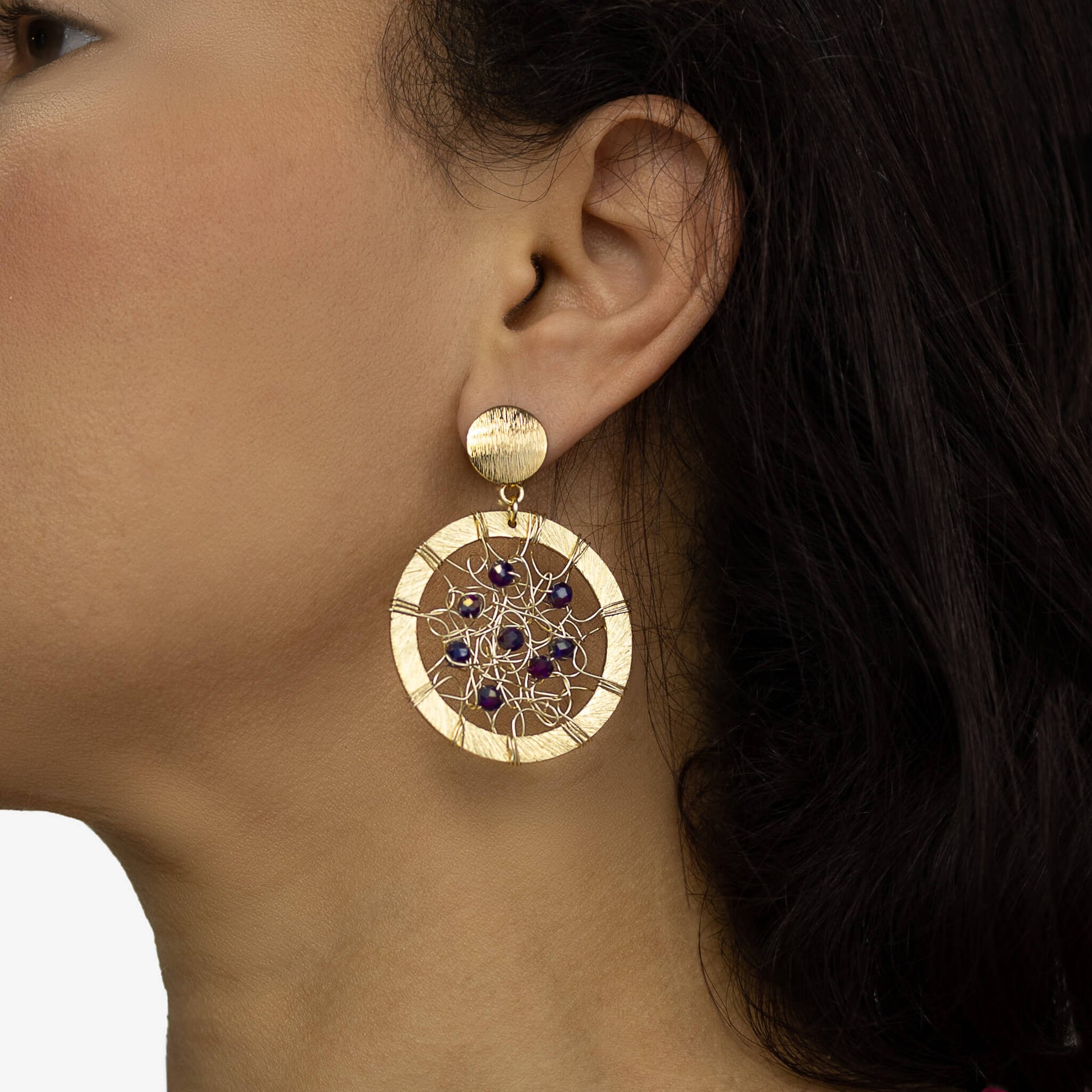 Janya Earrings on a model. Gold Color Wire Wrapped Earrings. Stud Earrings with Metallic Purple Crystal Beads Accent.