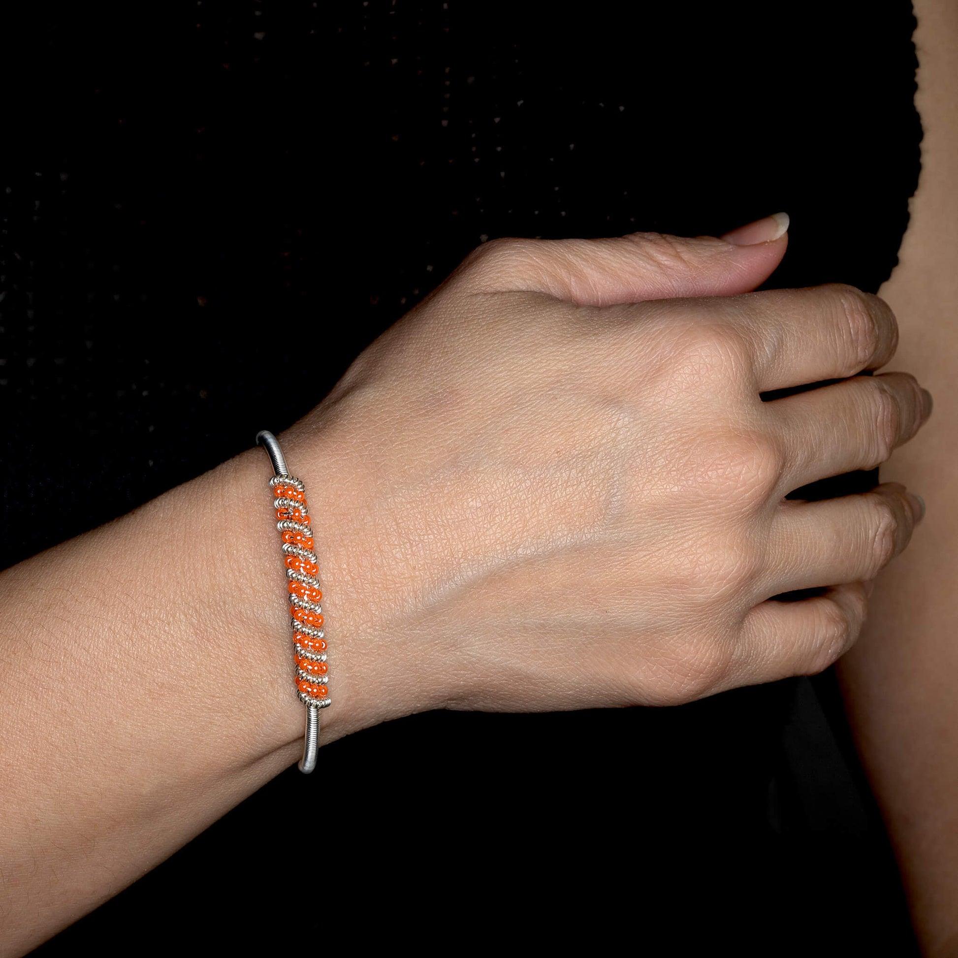 Siegen Silver Bracelet on a model. Silver Color Cuff Bracelet with Orange seed beads crystals. Wire wrapped bracelet. 